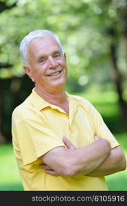 happy healthy and fit elderly man portrait in green background park