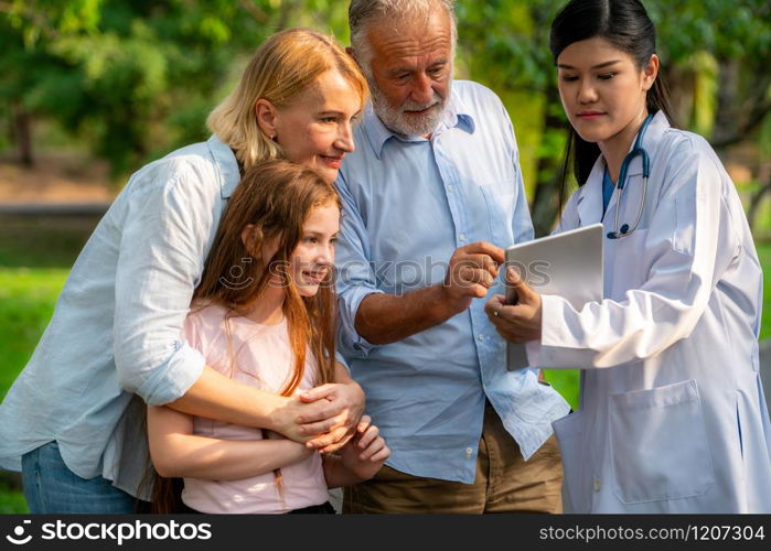 Happy healthy family and doctor talking in the park. People healthcare and medical staff service concept.. Happy healthy family and doctor talking in park.