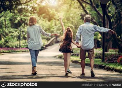 Happy healthy family walk together on path in the park in summer. Concept of family bonding.