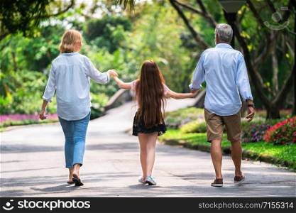 Happy healthy family walk together on path in the park in summer. Concept of family bonding.