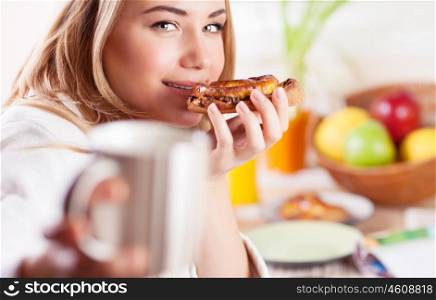 Happy healthy girl having breakfast, eating sweet tasty bun and drinking tea, enjoying morning meal at home&#xA;