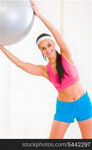 Happy healthy young girl doing exercises with fitness ball at living room&#xA;