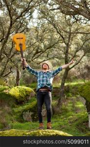 Happy hipster man with red beard and a guitar in the field