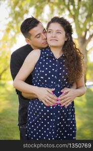 Happy Hispanic Man Hugs His Pregnant Wife Outdoors At The Park.