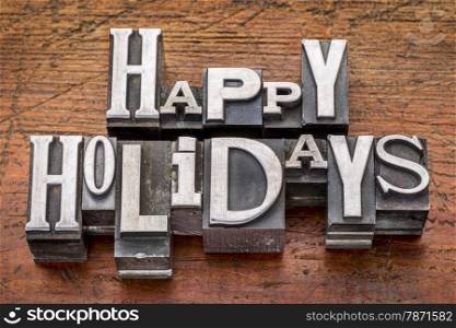 Happy Holidays greetings in vintage metal type printing blocks over grunge wood