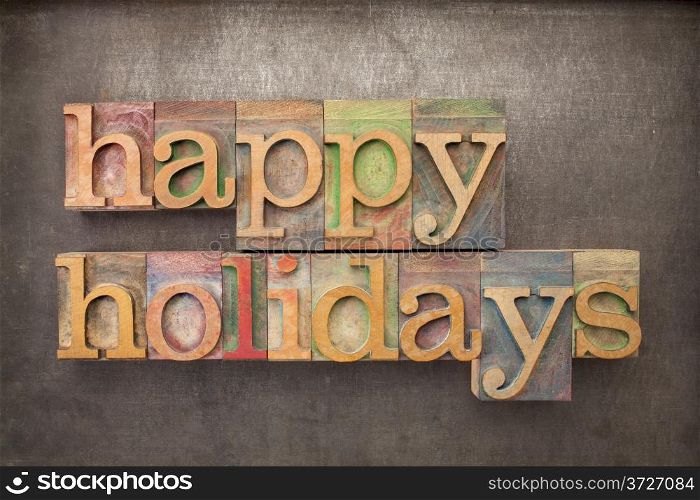 happy holidays - text in letterpress wood type against grunge metal background