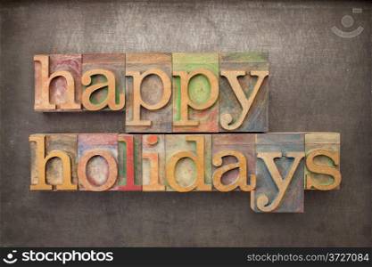 happy holidays - text in letterpress wood type against grunge metal background