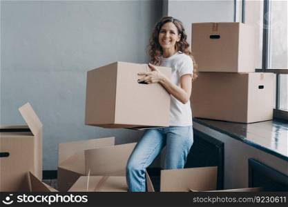Happy home owner. European girl carrying box. Hispanic woman unpacking boxes. New apartment, mortgage and independence concept. Real estate advertising mockup.. European girl carrying box. Hispanic woman unpacking boxes. Happy home owner.