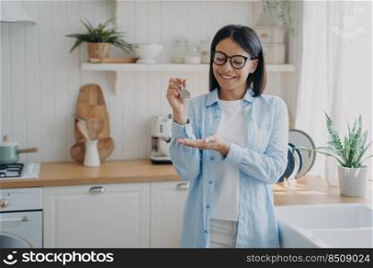 Happy homeowner. Smiling woman buyer renter of new home showing key of apartment, standing at modern kitchen. Female tenant demonstrating keys of dwelling. Real estate sale or rental.. Smiling woman homeowner renter of new home showing keys of dwelling. Real estate sale or rental