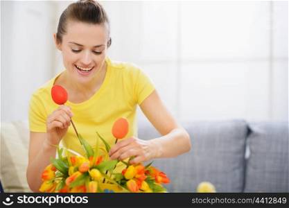 Happy housewife decorating bouquet of flowers for Easter