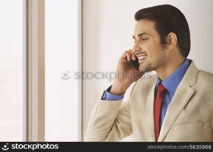 Happy Indian businessman using mobile phone in office