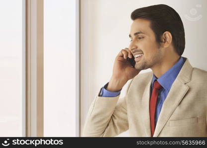 Happy Indian businessman using mobile phone in office