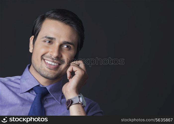 Happy Indian businessman using mobile phone over white background