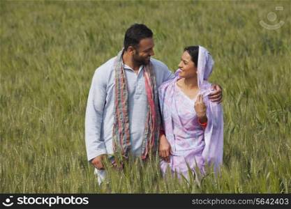 Happy Indian couple standing in wheat field