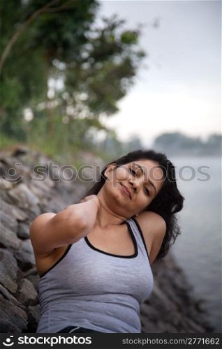 Happy indian girl on morning relaxing after exercise or jogging very near to lake