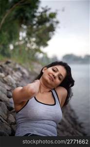 Happy indian girl on morning relaxing after exercise or jogging very near to lake