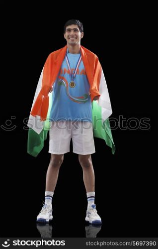 Happy Indian man in sportswear with Indian flag over black background