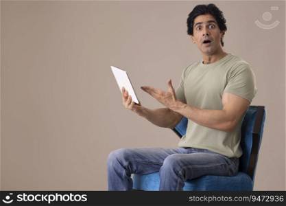 Happy Indian man posing in front of camera with tablet