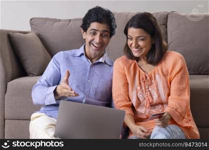Happy Indian middle age couple having fun after placing online order successfully