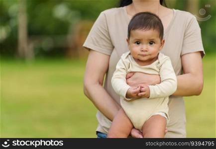 happy infant baby with mother holding in the park