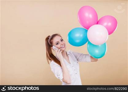 Happy joyful girl playing with colorful balloons while talking on mobile phone. Holidays, celebration and lifestyle concept. Studio shot on bright. girl talking phone while playing with balloons