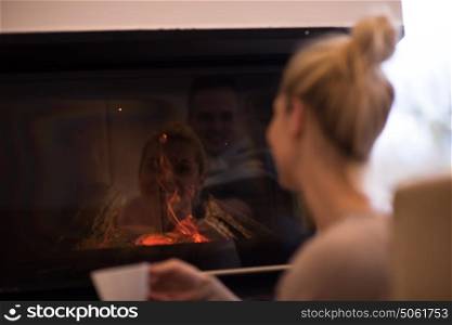 Happy joyful woman drinking cup of coffee relaxing at fireplace. Young beautiful girl with hot beverage heating warming up. autumn at home.