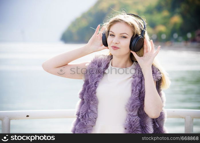 Happy joyful woman listening to music while being outdoor. Teenage female wearing headphones having fun on a walk.. Happy woman wearing headphones outdoor