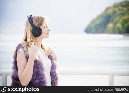 Happy joyful woman listening to music while being outdoor. Teenage female wearing headphones having fun on a walk.. Happy woman wearing headphones outdoor