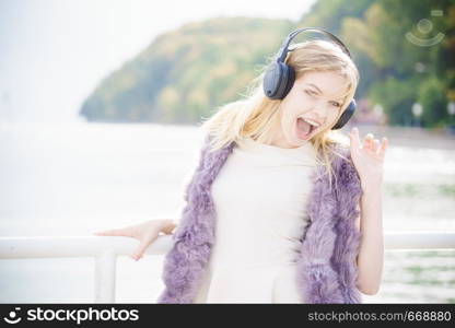 Happy joyful woman listening to music while being outdoor. Teenage female wearing headphones having fun on a walk.. Happy woman wearing headphones outdoor