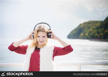 Happy joyful woman listening to music while being outdoor. Teenage female wearing headphones having fun on a walk.. Happy woman wearing headphones outdoor
