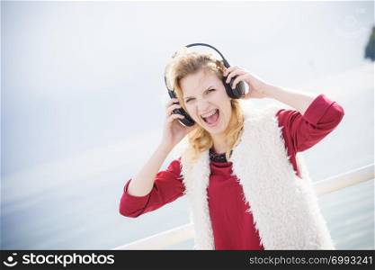 Happy joyful woman listening to music while being outdoor. Teenage female wearing headphones having fun on a walk.. Happy woman wearing headphones outdoor