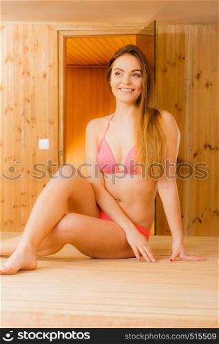 Happy joyful woman relaxing in wooden finnish sauna. Attractive girl in bikini resting. Spa wellbeing pleasure.. Happy woman relaxing in sauna. Spa wellbeing.