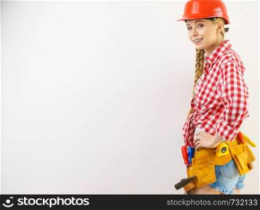 Happy joyful woman wearing helmet and checked shirt being positive about construction work.. Happy woman in protective helmet