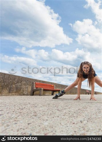 Happy joyful young woman wearing roller skates fooling around stretching her legs. Female being sporty having fun during summer time near sea.. Happy crazy woman wearing roller skates