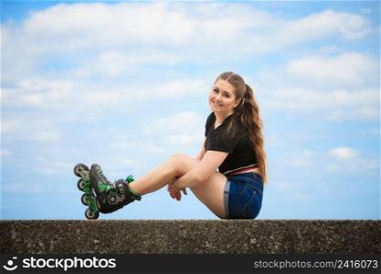 Happy joyful young woman wearing roller skates relaxing after long ride. Female being sporty having fun during summer time near sea.. Happy young woman wearing roller skates