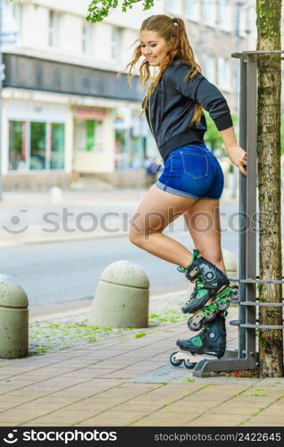 Happy joyful young woman wearing roller skates riding in town. Female being sporty having fun during summer time.. Young woman riding roller skates