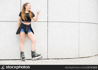 Happy joyful young woman wearing roller skates riding in town. Female being sporty having fun during summer time.. Young woman riding roller skates