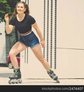 Happy joyful young woman wearing roller skates riding in town. Female being sporty having fun during summer time.. Young woman riding roller skates