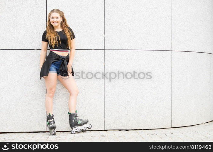 Happy joyful young woman wearing roller skates riding in town. Female being sporty having fun during summer time.. Young woman riding roller skates