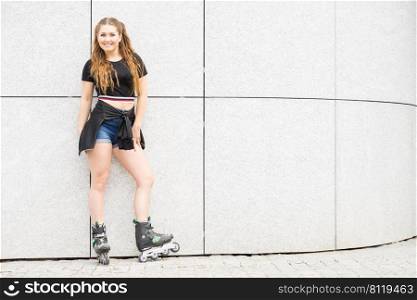 Happy joyful young woman wearing roller skates riding in town. Female being sporty having fun during summer time.. Young woman riding roller skates
