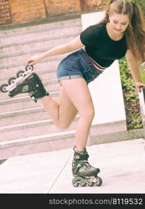 Happy joyful young woman wearing roller skates riding in town smelling flowers. Female being sporty having fun during summer time.. Young woman riding roller skates