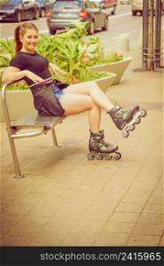 Happy joyful young woman wearing roller skates sitting in town. Female being sporty having fun during summer time.. Young woman sitting wearing roller skates