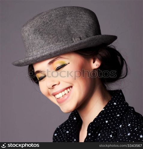 Happy joyful young woman with full makeup wearing a hat portrait.
