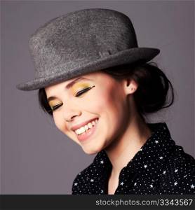 Happy joyful young woman with full makeup wearing a hat portrait.