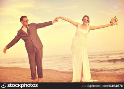 happy just married young couple celebrating and have fun at beautiful beach sunset