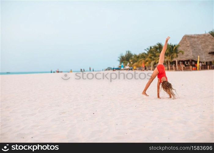 Happy kid enjoy beach tropical vacation and having fun. Adorable little girl at beach on her summer vacation