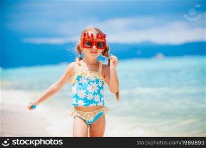 Happy kid enjoy beach tropical vacation and ready to swim. Adorable little girl at beach on her summer vacation