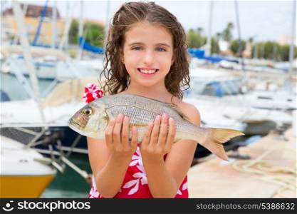 Happy kid fisherwoman with dentex fish catch in Mediterranean marina