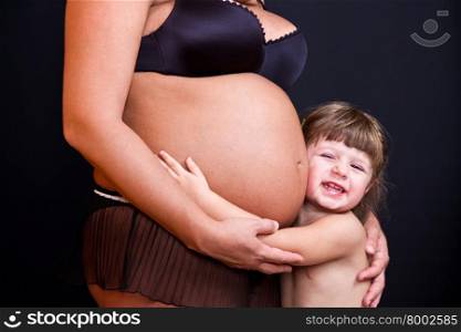 happy kid girl hugging pregnant mother&rsquo;s belly