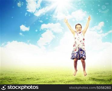 happy kid jumping. Photo of little girl jumping and raising hands against nature background